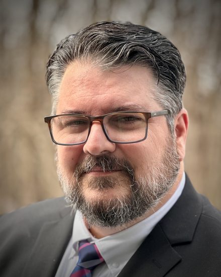 Tim Johnson, fractional CTO, photographed outdoors in a dark suit and tie.